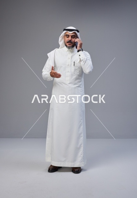 Saudi Man in Traditional Thobe Talking on Smartphone