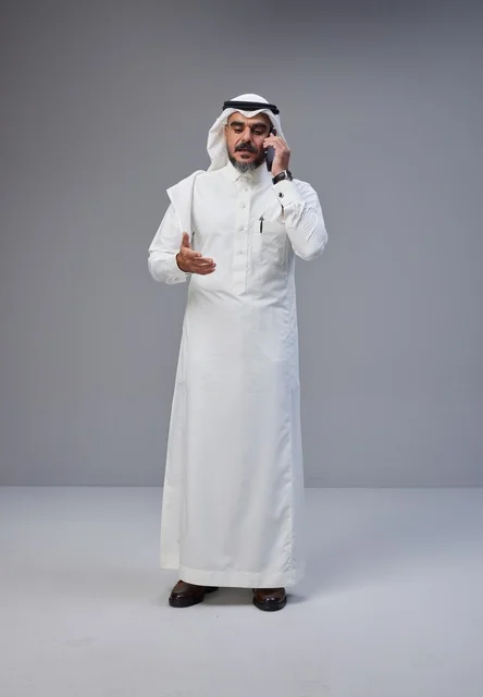 Saudi Man in Traditional Thobe Talking on Smartphone