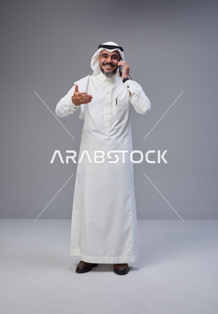 رجل سعودي بالزي التقليدي يتحدث عبر الهاتف الذكي