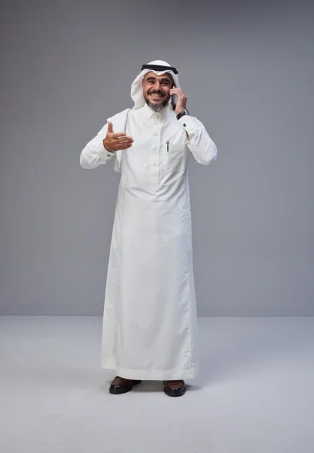 رجل سعودي بالزي التقليدي يتحدث عبر الهاتف الذكي