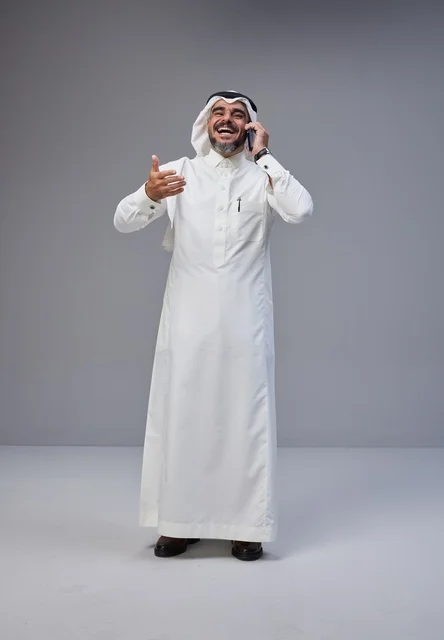رجل سعودي بالزي التقليدي يتحدث عبر الهاتف الجوال