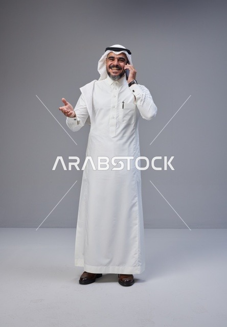 Saudi Man in Traditional Thobe Talking on Smartphone