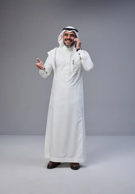 رجل سعودي بالزي التقليدي يتحدث عبر الهاتف الجوال
