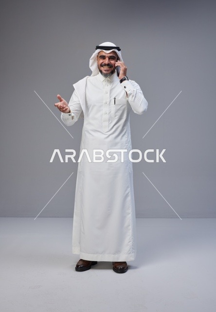 Saudi Man in Traditional Thobe Talking on Smartphone