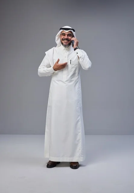 رجل سعودي بالزي التقليدي يتحدث عبر الهاتف الذكي