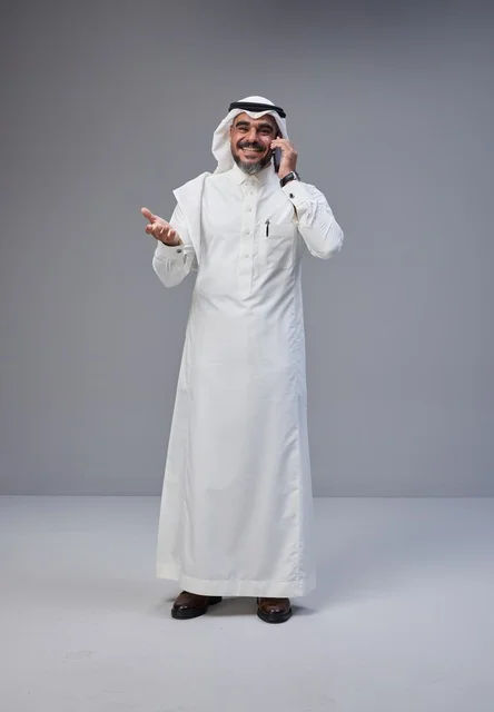 Saudi Man in Traditional Thobe Talking on Smartphone