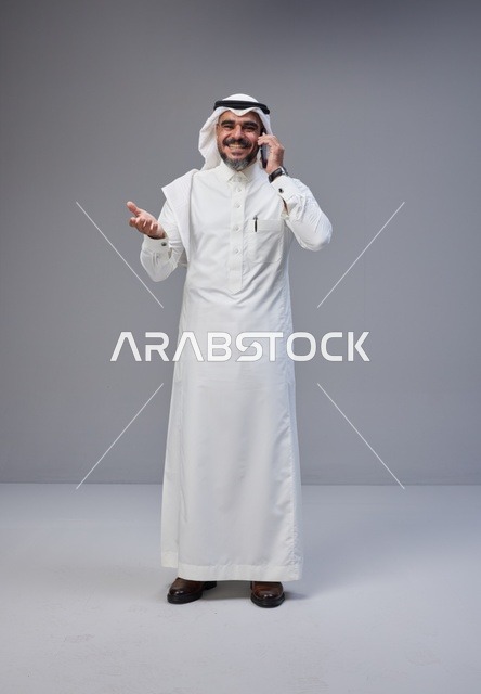 Saudi Man in Traditional Thobe Talking on Smartphone