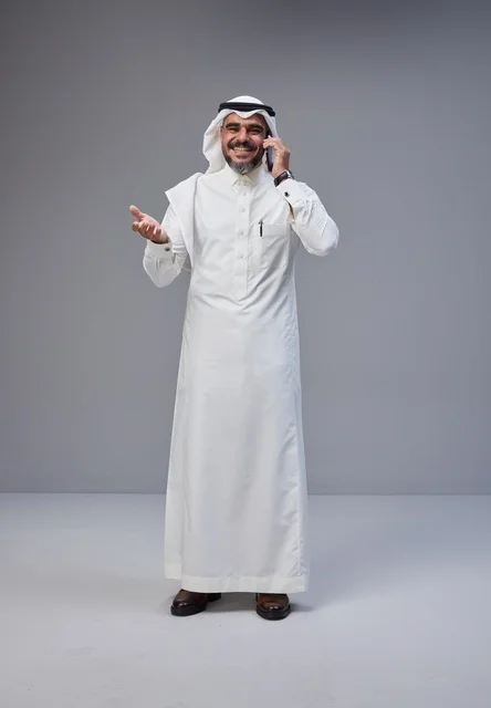 Saudi Man in Traditional Thobe Talking on Smartphone