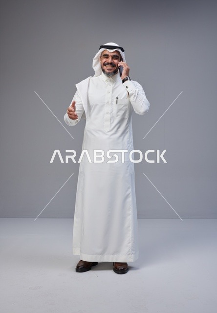 رجل سعودي بالزي التقليدي يتحدث عبر الهاتف الجوال