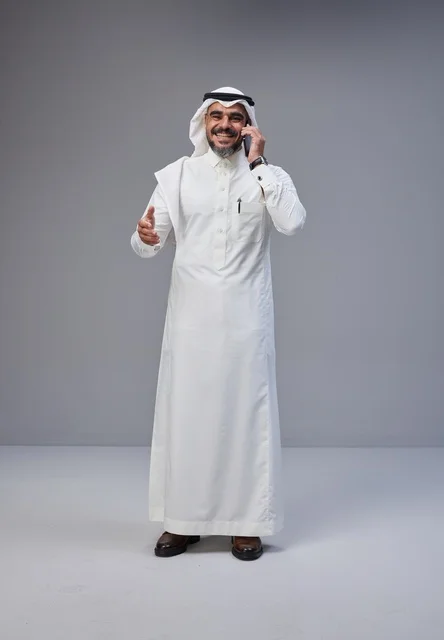 Saudi Man in Traditional Thobe Talking on Smartphone