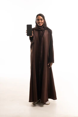 امرأة سودانية بعباية بنية تحمل هاتف ذكي