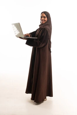 امرأة سعودية بالعباءة البنية مع جهاز كمبيوتر محمول