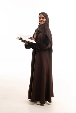 امرأة سعودية بعباءة بنية تحمل كتاباً بخلفية بيضاء