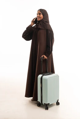 امرأة سعودية مع حقيبة سفر تتحدث بالهاتف