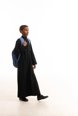 طالب سوداني بالثوب الأسود مع حقيبة مدرسية زرقاء