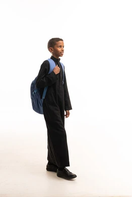 طفل سعودي بالثوب الأسود يحمل حقيبة مدرسية زرقاء