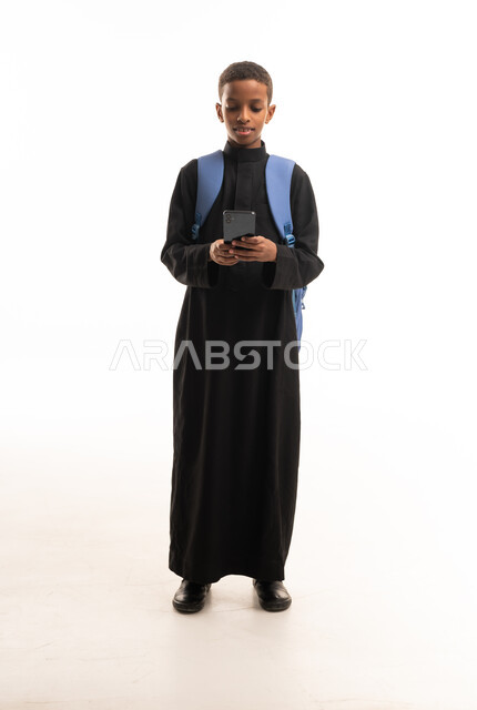 صبي أفريقي بالثوب السعودي الأسود يستخدم الجوال