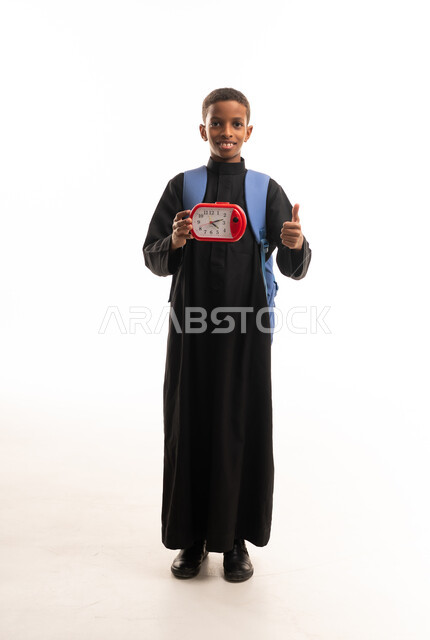 طفل سوداني بالثوب الأسود يحمل ساعة وحقيبة مدرسية