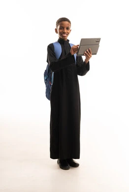 طالب سعودي بالثوب الأسود يحمل جهازاً لوحياً وحقيبة