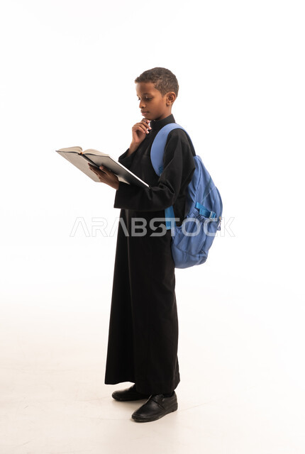 Saudi Boy in Black Thobe Reading Book on White Background