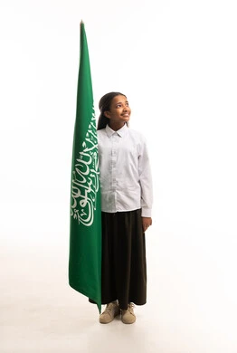 طالبة سعودية بالزي المدرسي مع علم المملكة العربية السعودية