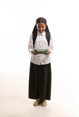 طالبة سعودية بالزي المدرسي مع صندوق الغداء