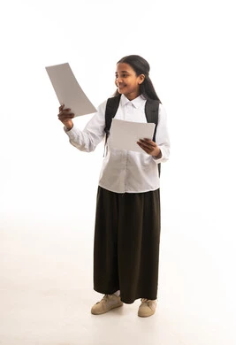 طالبة سعودية بالزي المدرسي تمسك أوراقاً خلفية بيضاء