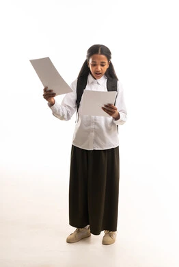 طالبة سعودية بالزي المدرسي تمسك أوراق الاختبار