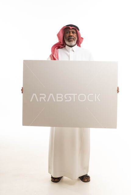 رجل سعودي مسن يحمل لوحة بيضاء فارغة في استوديو