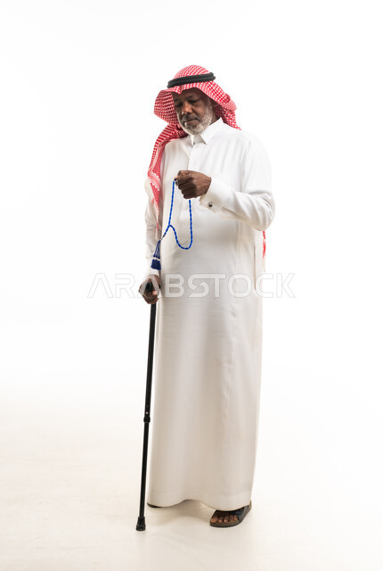 رجل سعودي مسن مع عكاز وسبحة بزي تقليدي