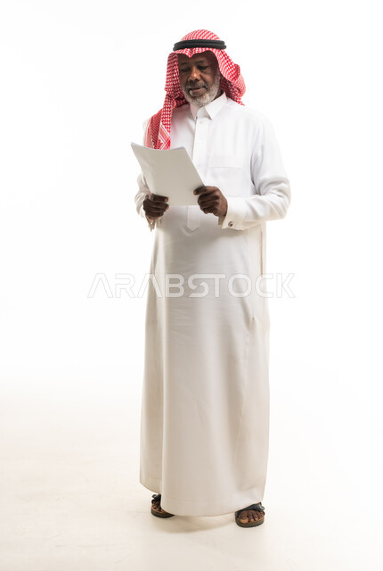 رجل سعودي مسن يقرأ وثيقة على خلفية بيضاء