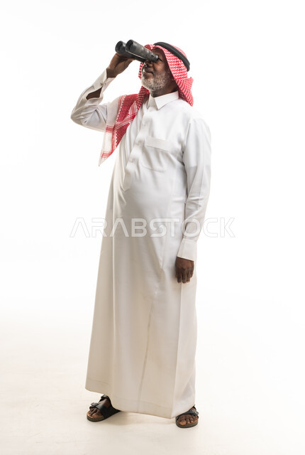 رجل سعودي بالزي التقليدي يستخدم المنظار