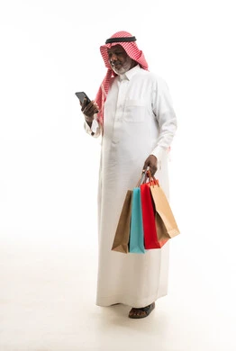 رجل سعودي مسن مع حقائب تسوق وهاتف ذكي
