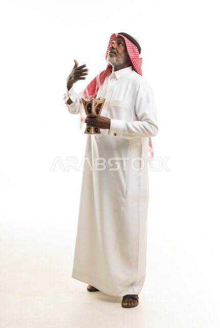 رجل سعودي مسن يحمل مبخرة تقليدية بخلفية بيضاء