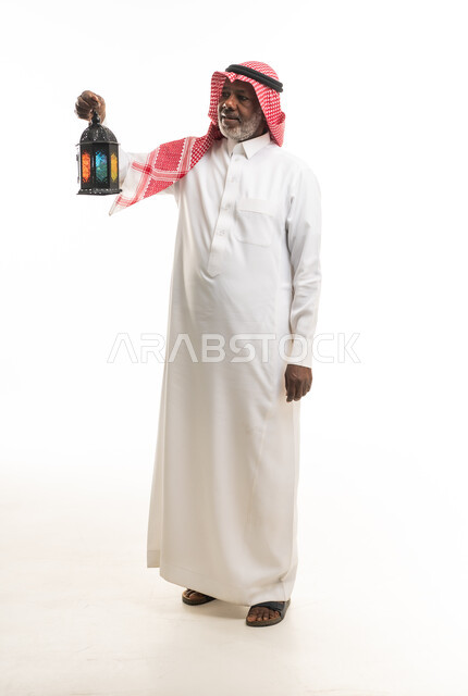 رجل سعودي يمسك فانوس رمضان بخلفية بيضاء