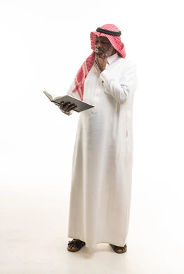 رجل سعودي مسن يقرأ كتاباً بخلفية بيضاء