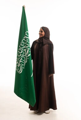 امرأة سعودية بالعباءة مع العلم الوطني السعودي