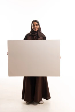 امرأة سعودية تحمل لوحة بيضاء فارغة في الاستوديو