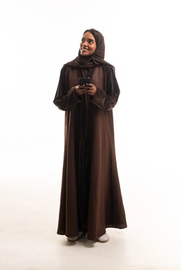 امرأة سعودية بعباءة بنية تستخدم الهاتف الذكي