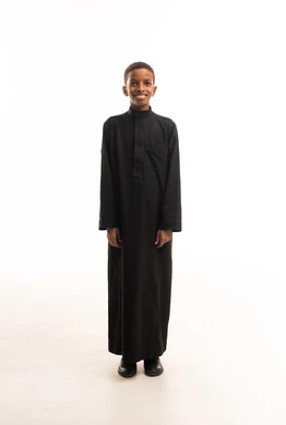 طفل سعودي بالثوب التقليدي الأسود على خلفية بيضاء