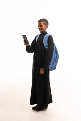 طفل سعودي يرتدي الثوب الأسود يستخدم هاتف ذكي متنقل