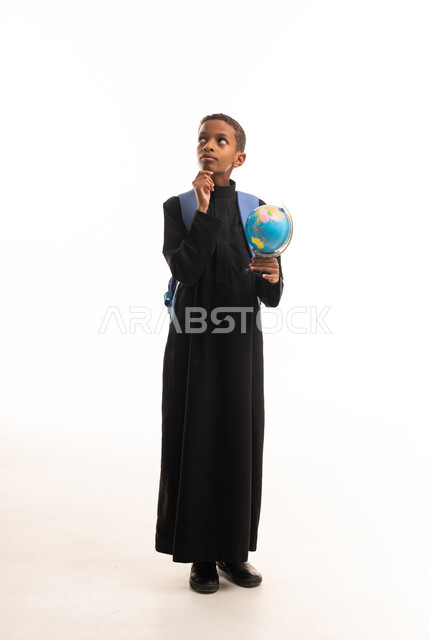 طالب عربي أسمر يفكر مع مجسم الكرة الأرضية بالثوب الأسود