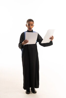 طفل سعودي بالثوب الأسود يحمل أوراق مدرسية مندهش