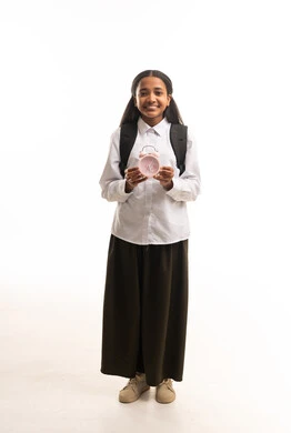 طالبة مدرسة سعودية بالزي المدرسي تمسك ساعة منبه