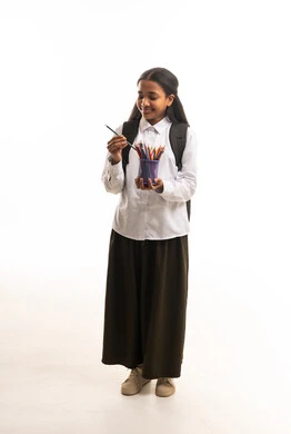 طالبة سعودية بالزي المدرسي مع حقيبة وأقلام ملونة