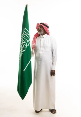 رجل سعودي مسن يرفع علم المملكة العربية السعودية في استوديو