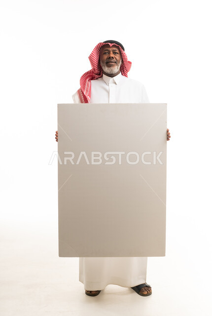 رجل سعودي مسن يحمل لوحة بيضاء فارغة في الاستوديو
