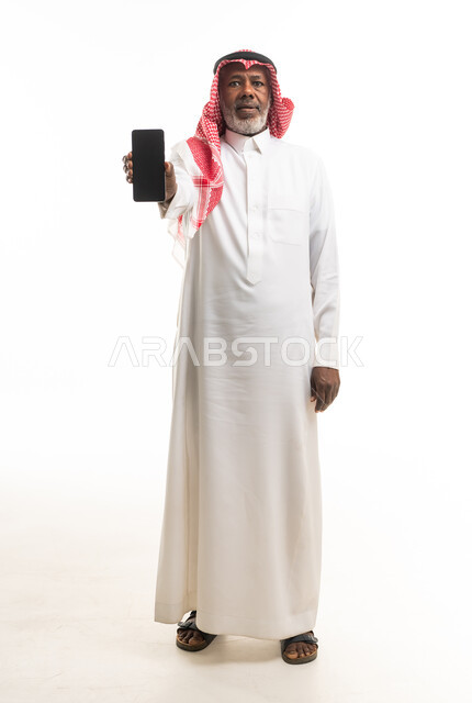 رجل سعودي مسن يحمل هاتف ذكي بخلفية بيضاء