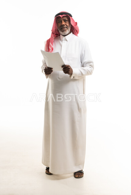 رجل سعودي مسن بالزي التقليدي يحمل أوراقاً