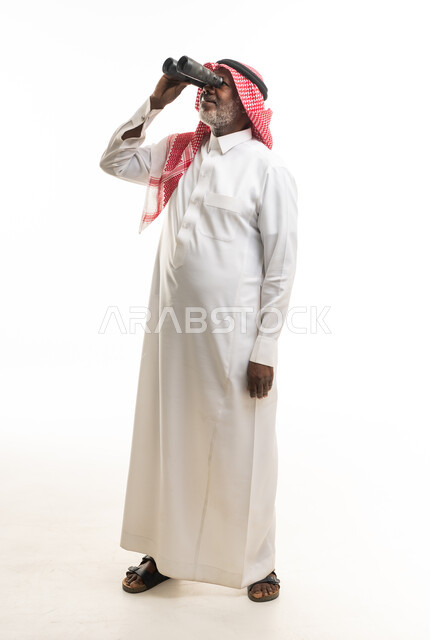 رجل سعودي بالثوب التقليدي يستخدم المنظار بخلفية بيضاء